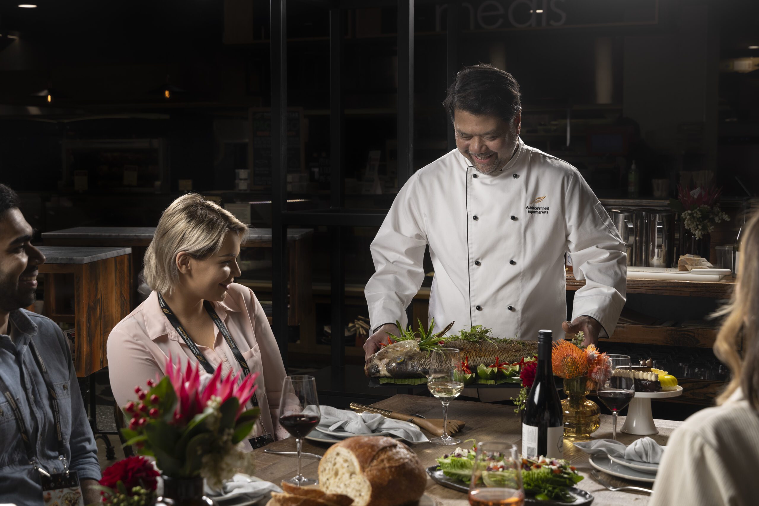 Women sits at table whilst a man serves her food