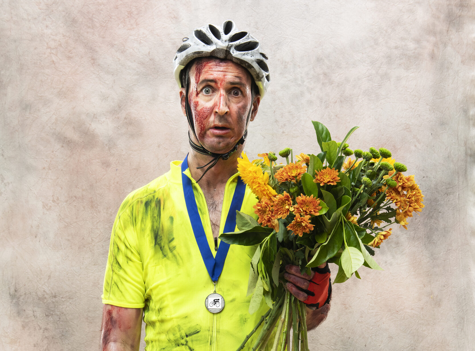 Man in cycling gear looks disheveled whilst holding a bunch of flowers and a medal around his neck