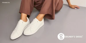 A woman's legs in white sneakers resting on a smooth gray floor.