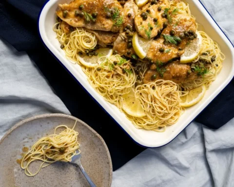 A plate of chicken and noodles garnished with fresh lemon slices.
