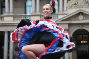A woman dances joyfully in a vibrant red, white, and blue dress.