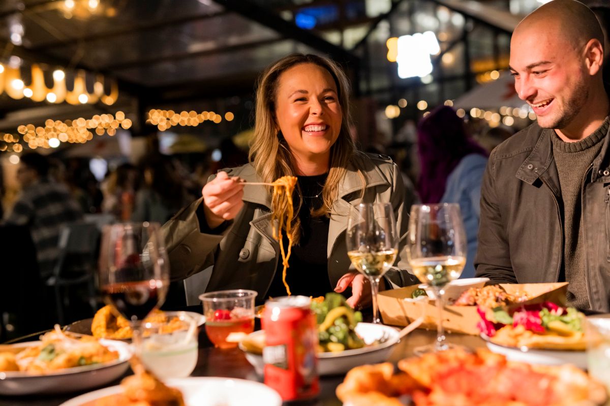 A man and woman enjoying a meal together at a restaurant, seated at a table with food and drinks in front of them.