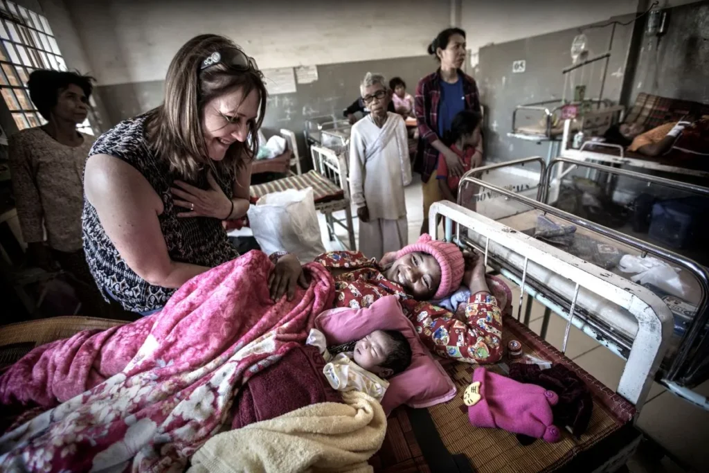 A woman cradles a newborn baby in her arms while resting in a hospital bed.