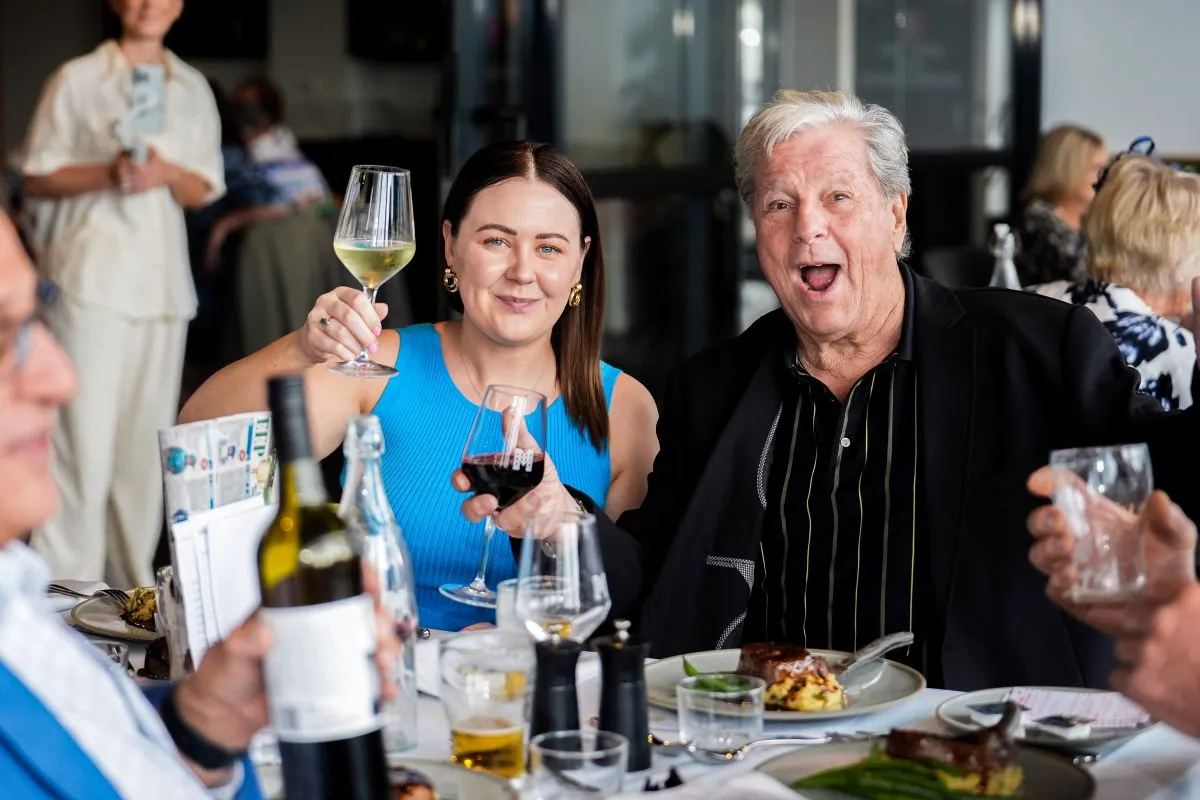 A group of people enjoying dinner at a table, with wine glasses raised in a toast.