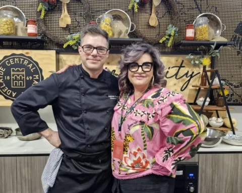 A man and woman stand together in a modern kitchen, smiling and looking at the camera.