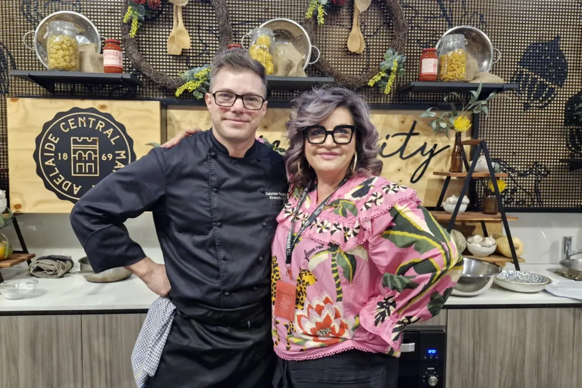 A man and woman stand together in a modern kitchen, smiling and looking at the camera.