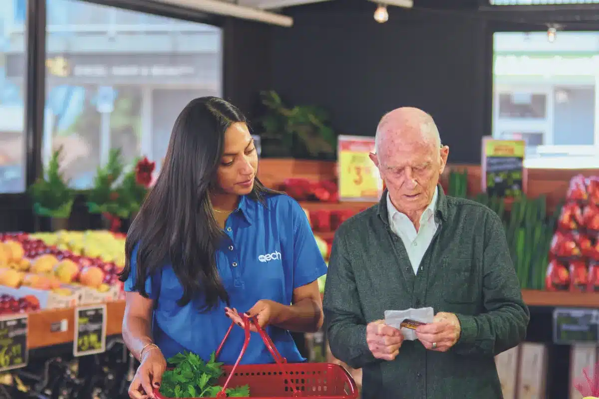 A man and woman shopping together in a grocery store aisle, surrounded by various food products.