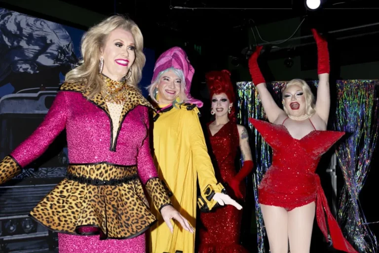 A group of women dressed in colorful costumes and elaborate makeup, smiling and posing together for the camera.