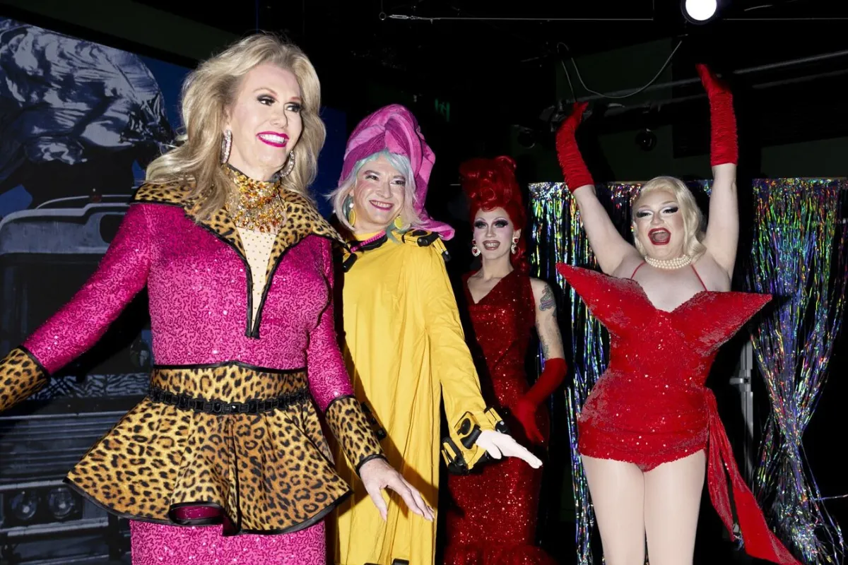A group of women dressed in colorful costumes and elaborate makeup, smiling and posing together for the camera.