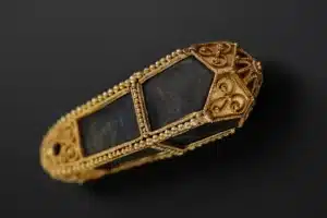 A gold and black stone pendant featuring intricate designs and patterns.