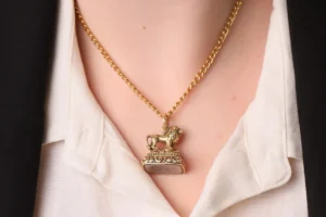 A woman wearing a gold necklace featuring a lion pendant.