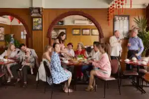 A group of people dining together at tables in a lively restaurant setting.