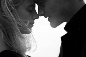 Black and white photo of a man and woman standing together, both smiling at the camera.