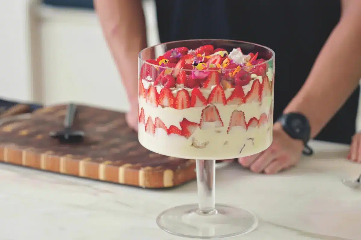 A person slices fresh strawberries to prepare them for a dessert.
