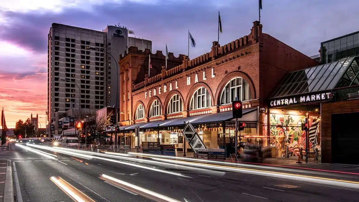 A city street featuring a prominent clock tower alongside a classic building under a clear blue sky.