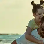 A man and a little girl play together on the beach, enjoying the sun and sand.