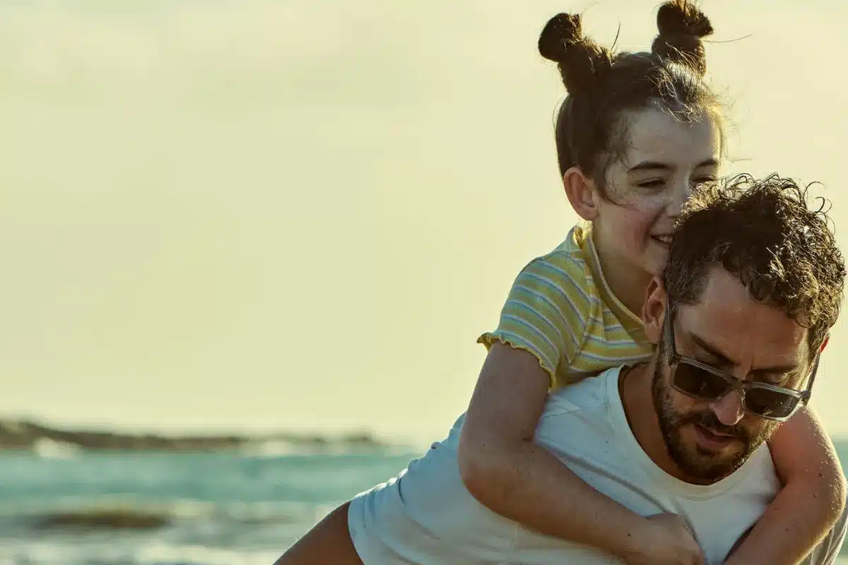 A man and a little girl play together on the beach, enjoying the sun and sand.