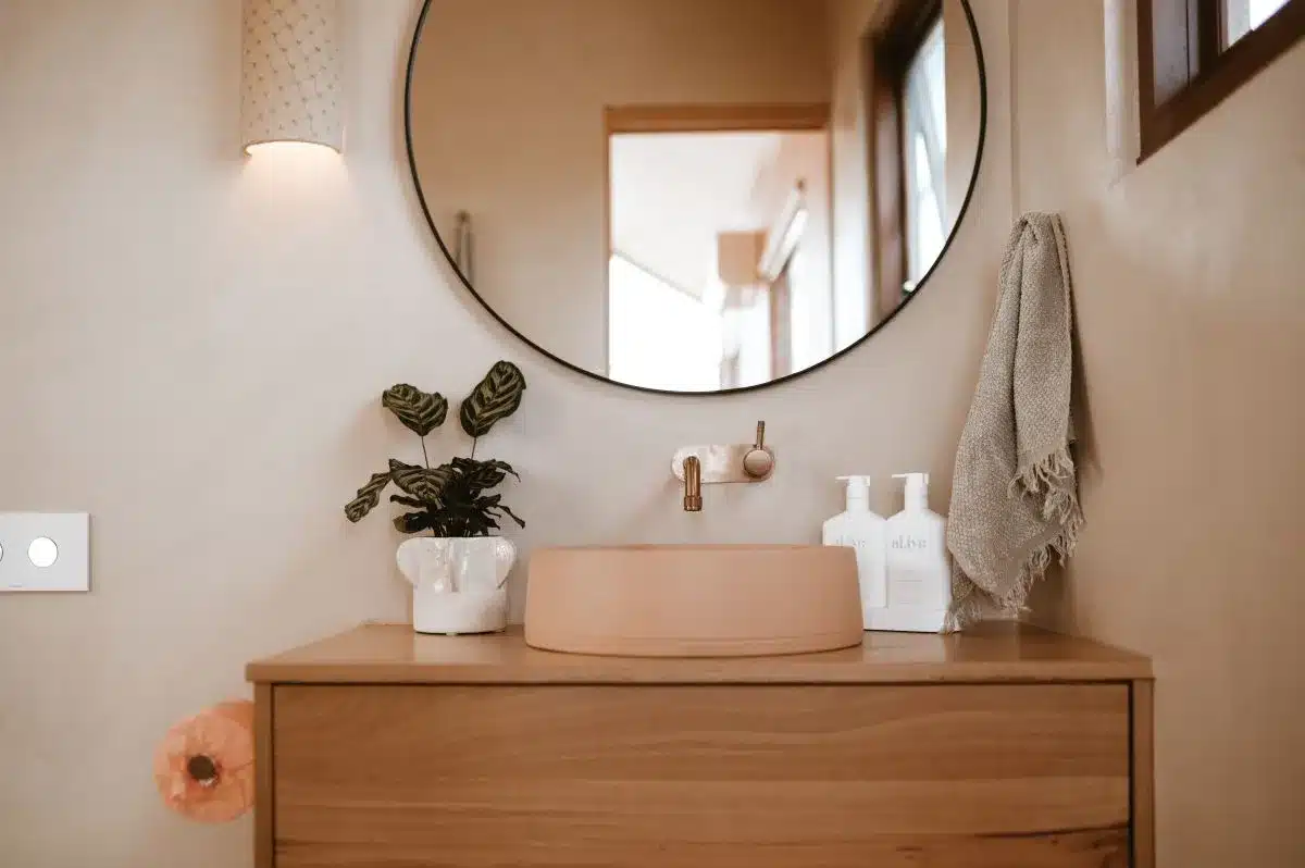 A bathroom featuring a wooden vanity and a round mirror above it, creating a warm and inviting atmosphere.