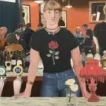 A painting depicting a man standing behind a bar, with bottles and glasses arranged on the counter.