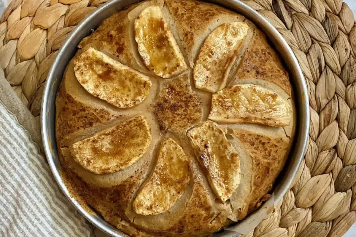 A cake on a plate surrounded by fresh apples, showcasing a delightful dessert presentation.
