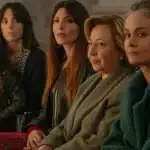 A group of women sitting together in a row, smiling and engaged in conversation.
