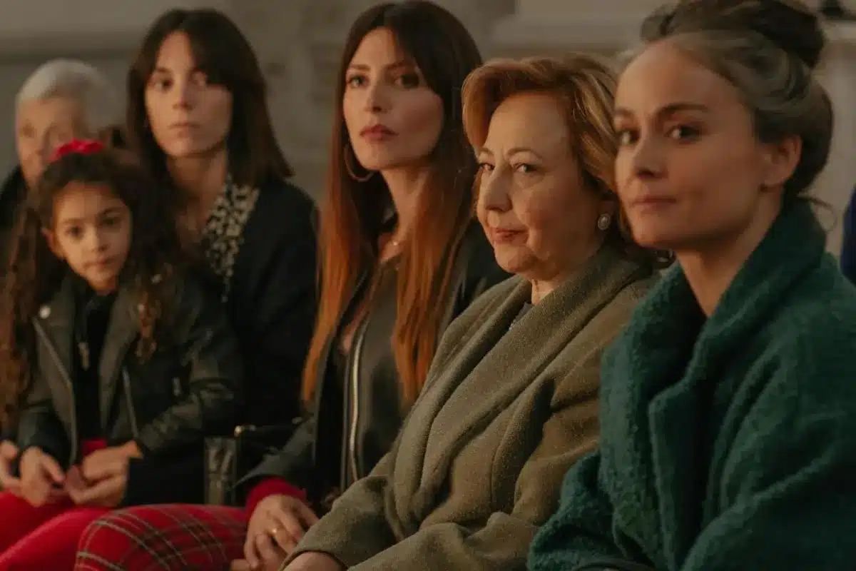A group of women sitting together in a row, smiling and engaged in conversation.