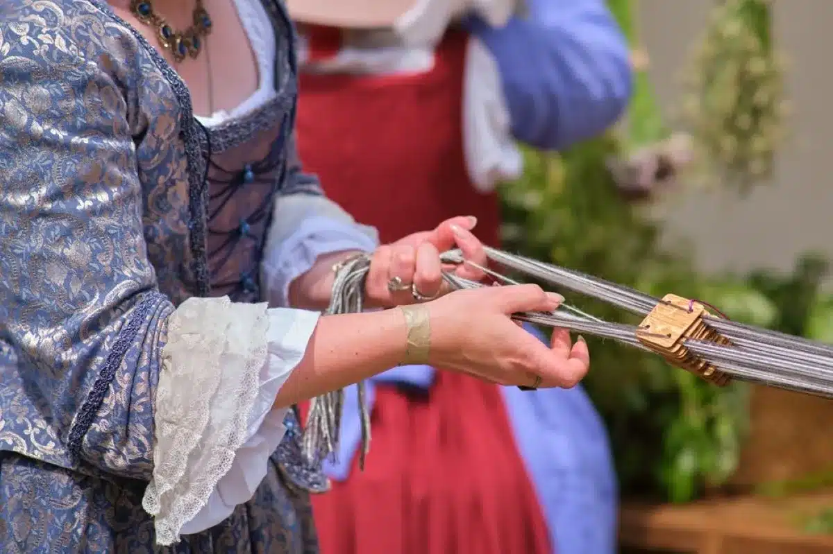 A woman in a renaissance dress holds a pair of scissors, poised as if ready to cut fabric or thread.