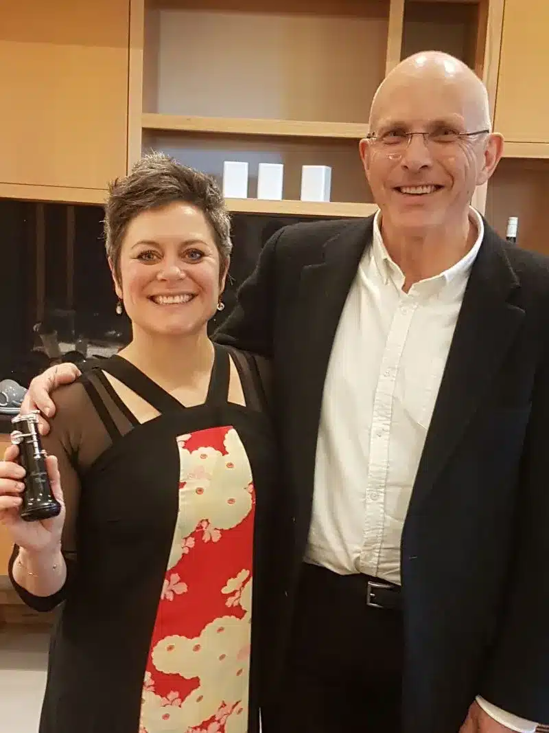 Man and woman stand, smiling directly at camera.