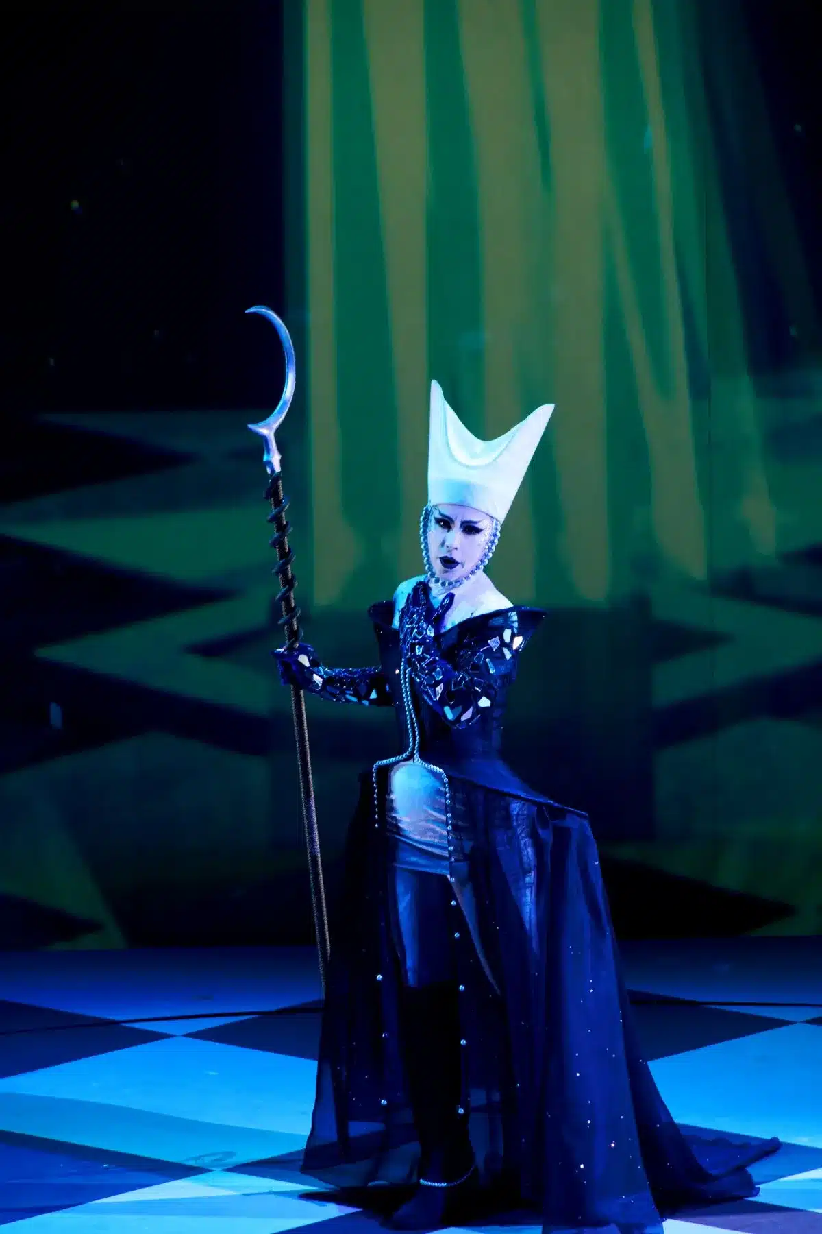 A woman in a witch costume holds a staff, exuding a mystical and enchanting presence.