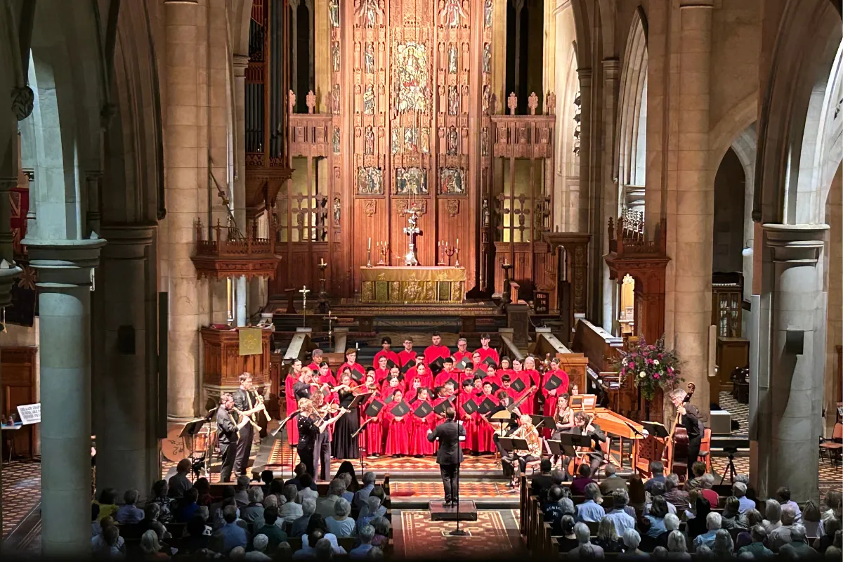 A choir performs in a church, accompanied by a large organ, creating a harmonious atmosphere.