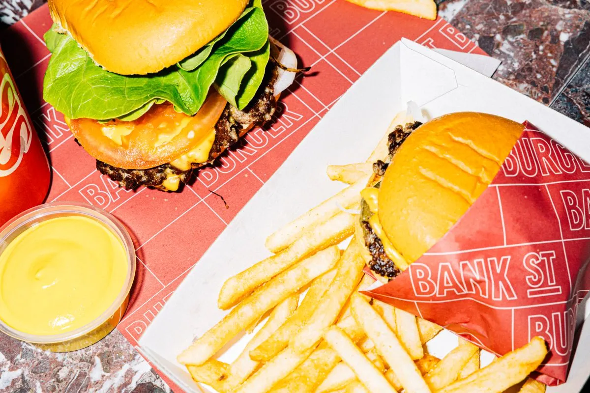 A burger with lettuce and tomato alongside a serving of golden fries on a wooden table.