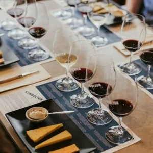 Guests sampling various wines at a rustic winery, surrounded by barrels and vineyard views.