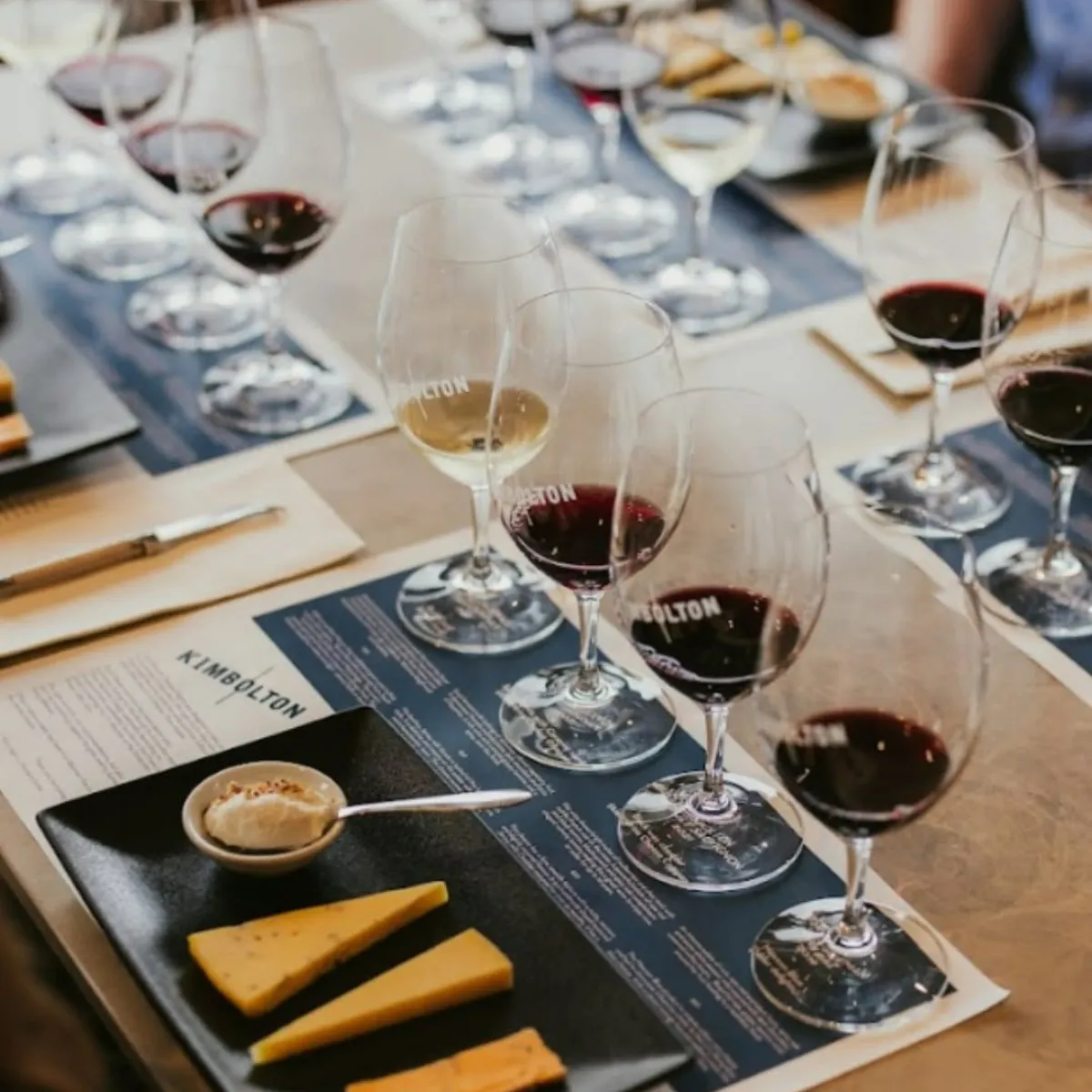 Guests sampling various wines at a rustic winery, surrounded by barrels and vineyard views.