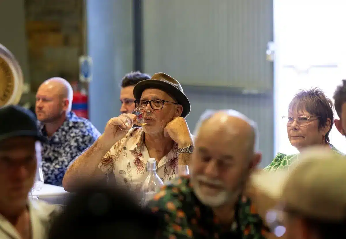 A group of people seated at tables, each with glasses, engaged in conversation and enjoying their time together.
