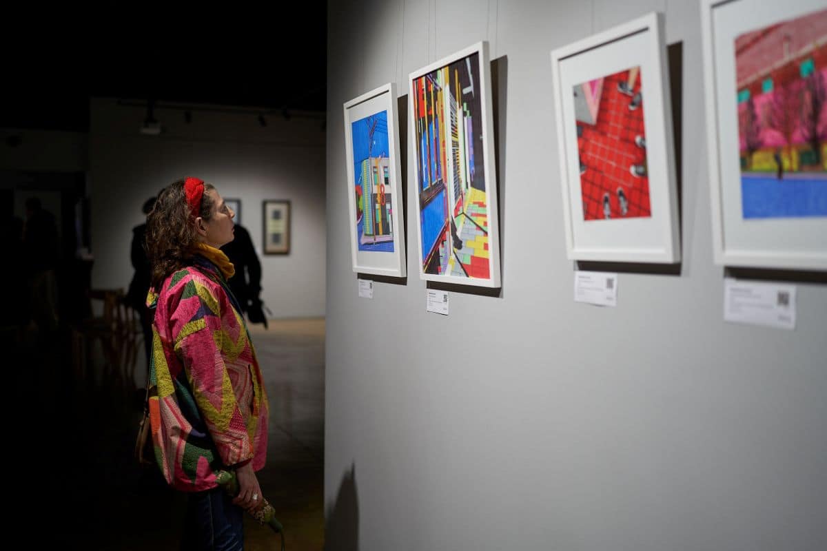 A woman observes artwork displayed in an art gallery, engaging with the creative pieces around her.