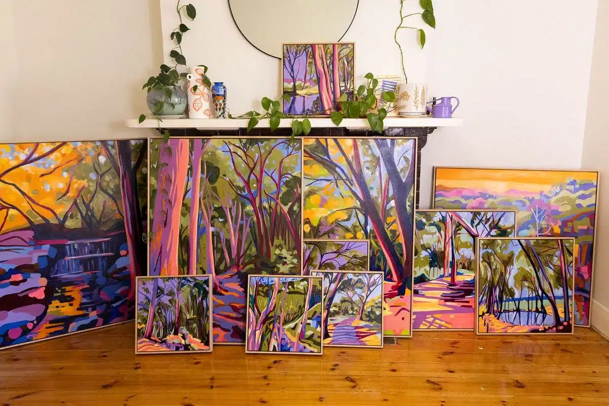 An inviting room with a fireplace, a central table, and an array of framed paintings decorating the walls.