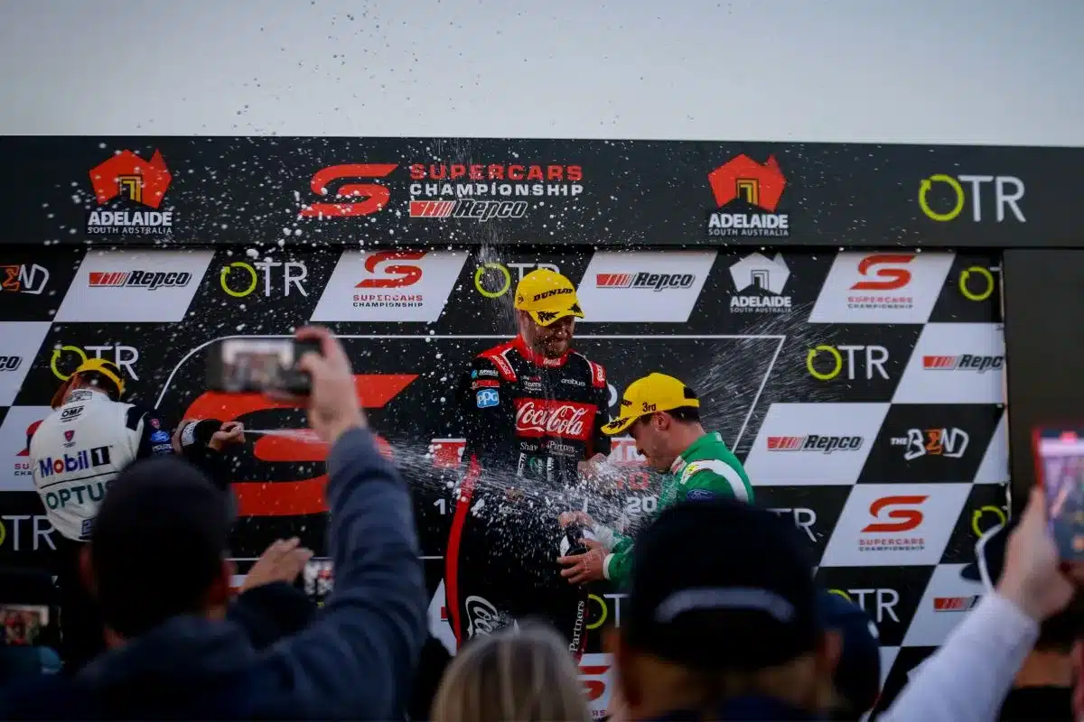 A man sprays water on a race podium, preparing it for the next event or celebration.