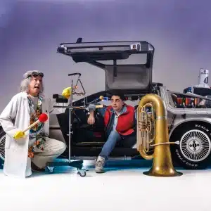 Two individuals in costumes pose beside a DeLorean car from Back to the Future, showcasing a fun, nostalgic moment.