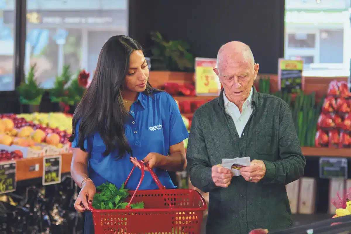 Female carer shopping with elderly man.