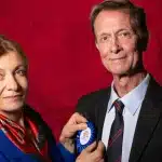 A man and woman stand side by side, smiling for a photo