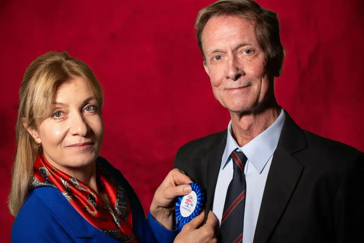 A man and woman stand side by side, smiling for a photo