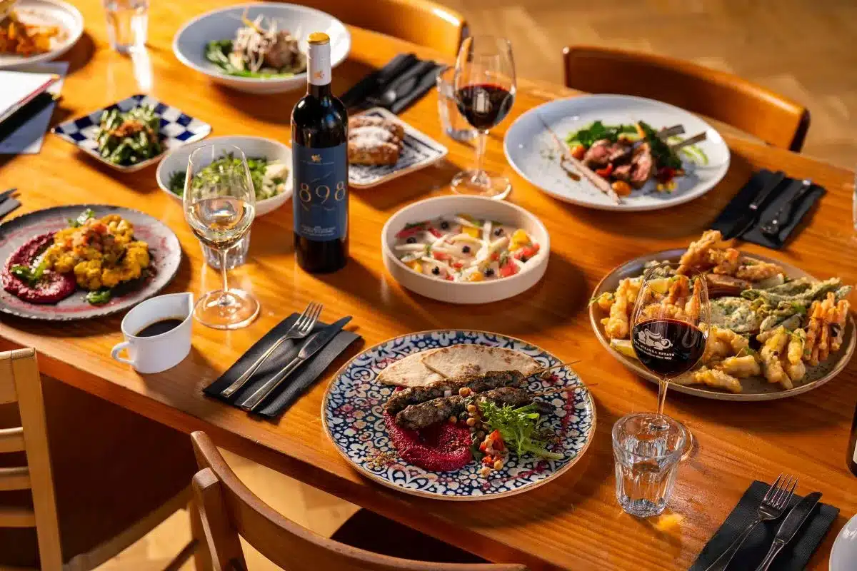 A table set with various plates of food and glasses of wine, creating an inviting dining atmosphere.