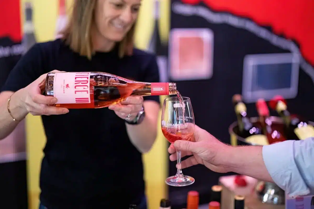 A woman elegantly pours red wine from a bottle into a glass, showcasing a moment of celebration.