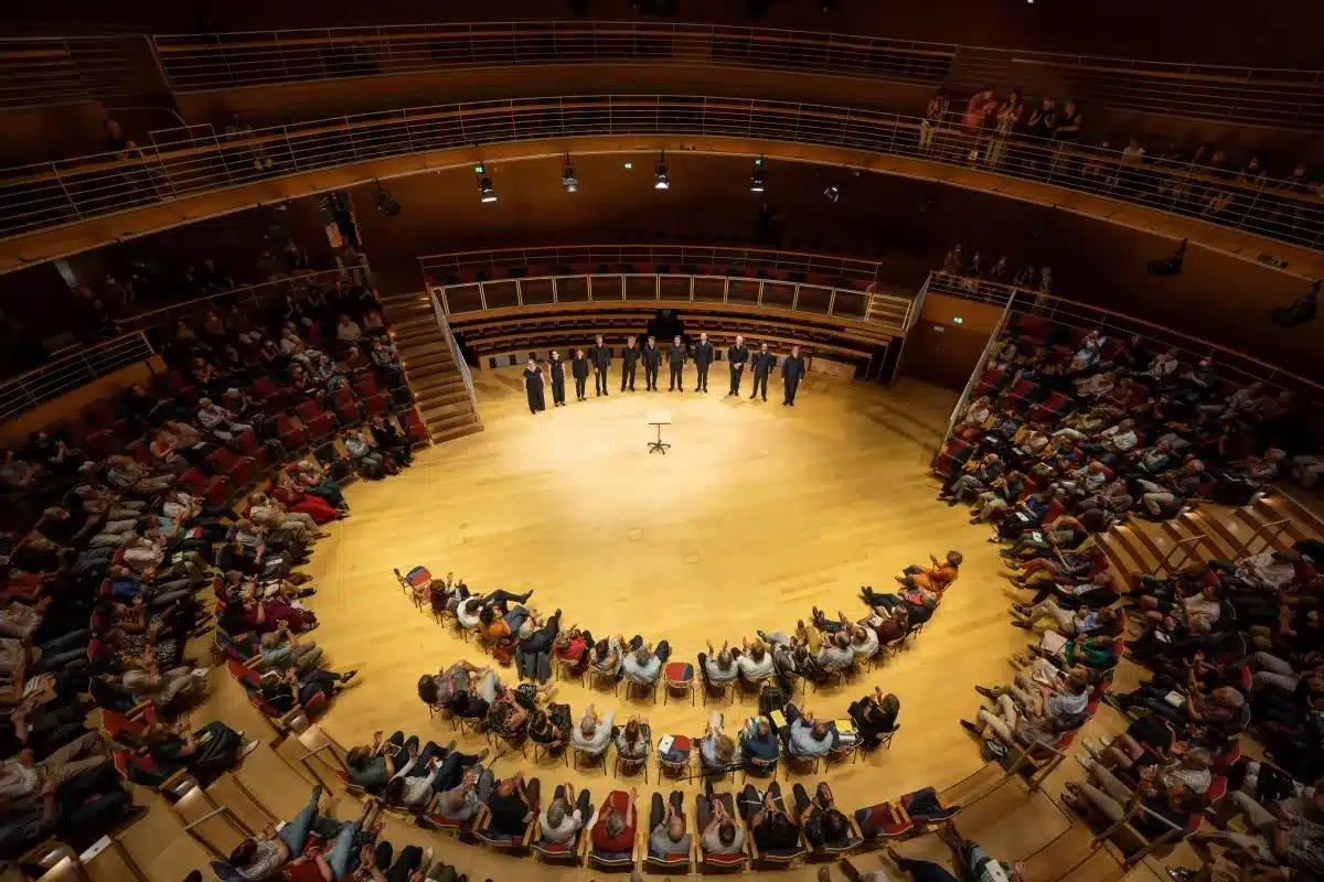 A large auditorium filled with people seated in rows of chairs, engaged in an event or presentation.