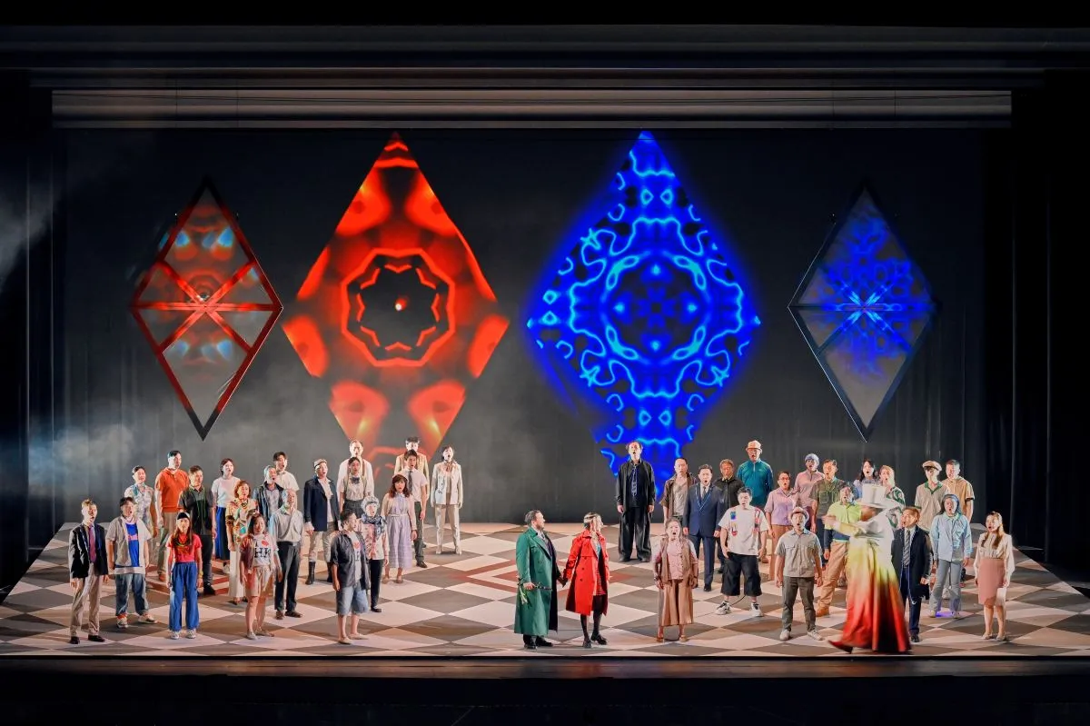 A group of people stands on stage with a large screen displaying visuals behind them.