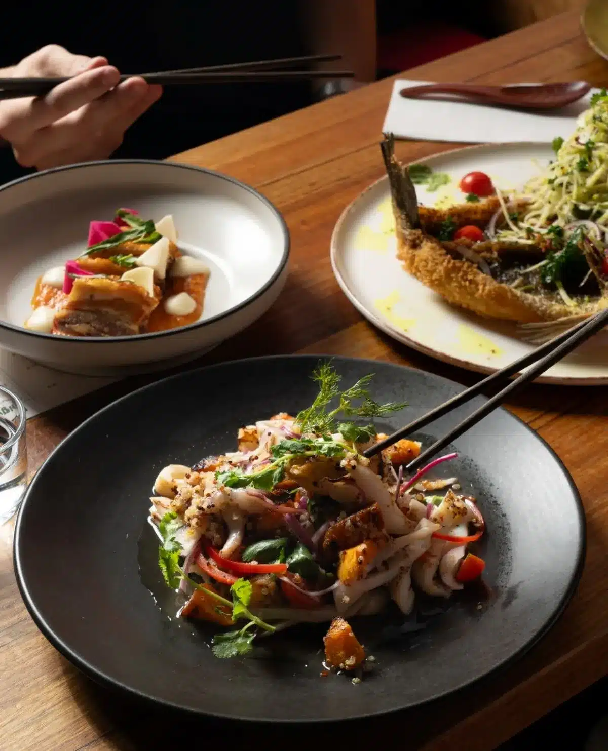  A table set with various plates of food and chopsticks arranged neatly beside each plate.
