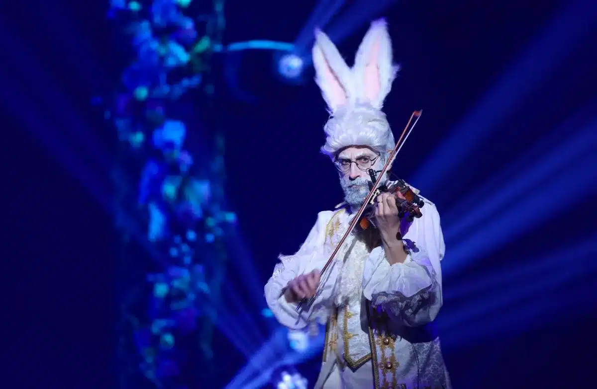 The White Rabbit in Cirque Alice plays violin.