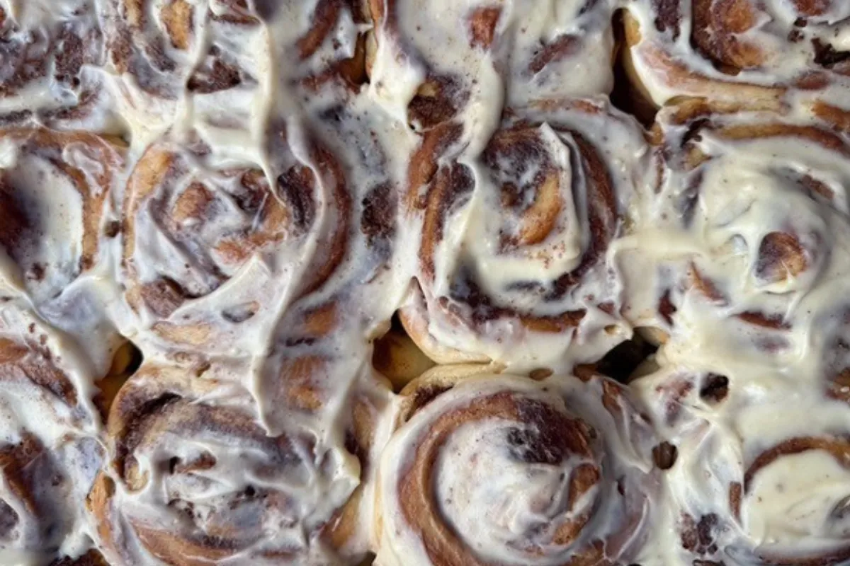 A pan filled with freshly baked cinnamon rolls topped with a generous layer of creamy icing.