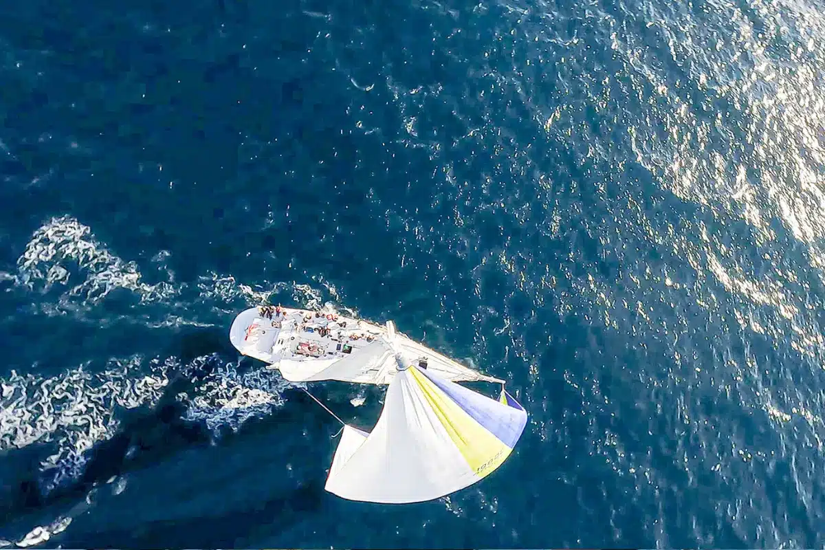A sailboat gliding across the ocean, with gentle waves and a clear blue sky in the background.