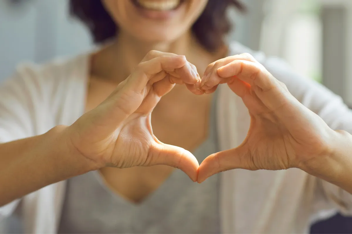 Woman making heart shape with hands.